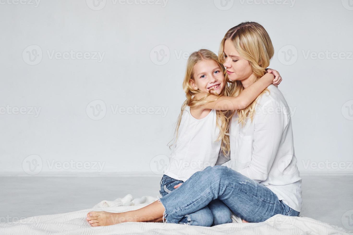 madre con sua figlia insieme è su il terra nel il studio con bianca sfondo foto