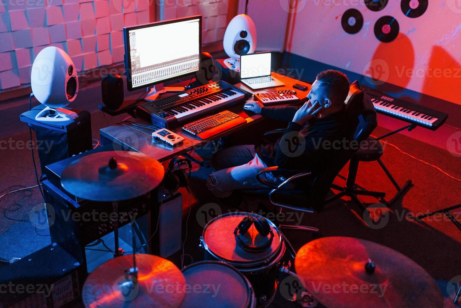 suono ingegnere Lavorando e miscelazione musica in casa nel il studio vicino tamburo kit foto