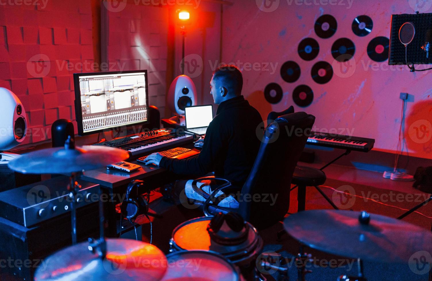 suono ingegnere Lavorando e miscelazione musica in casa nel il studio vicino tamburo kit foto