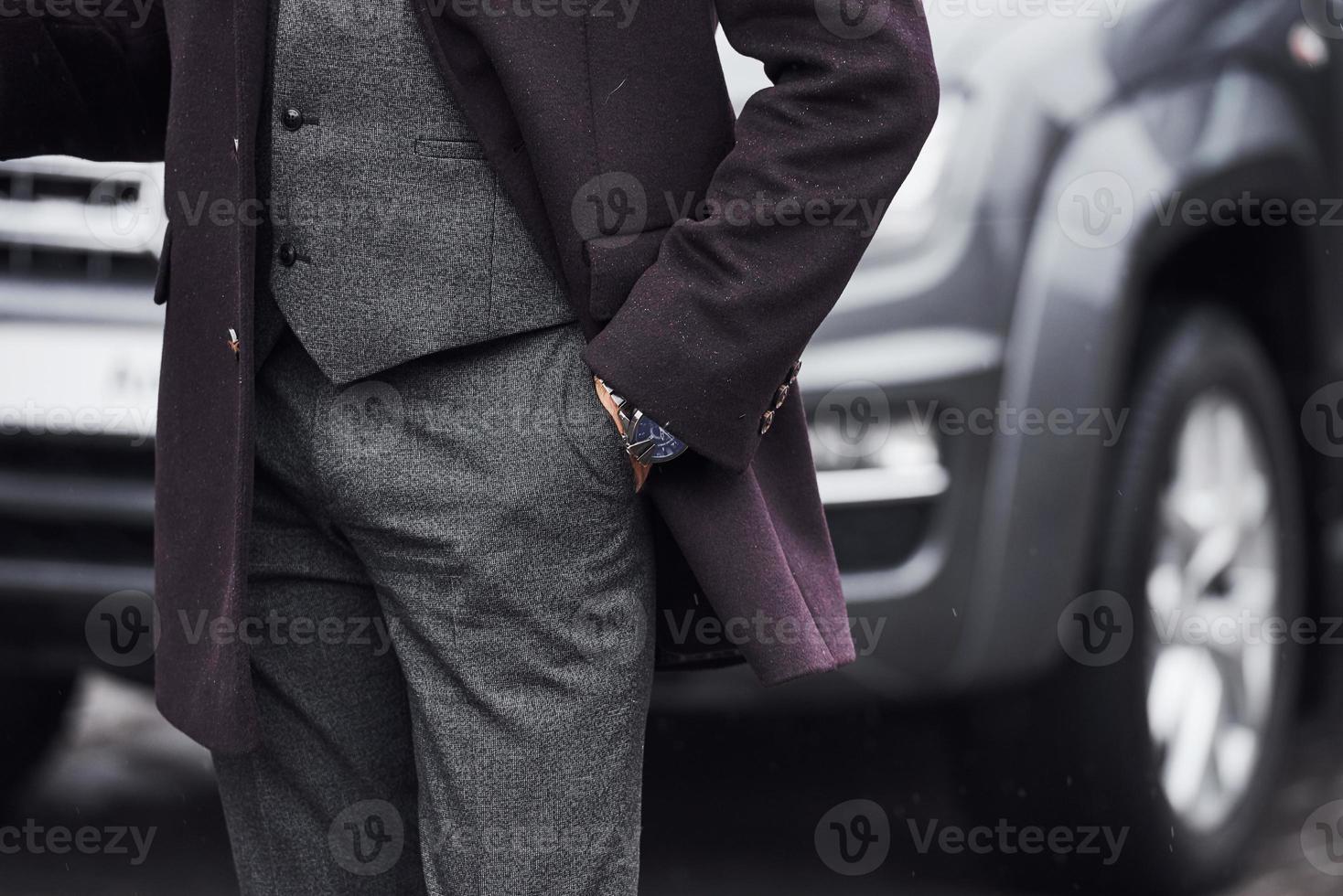 alla moda uomo in piedi all'aperto su il strada vicino il suo auto foto