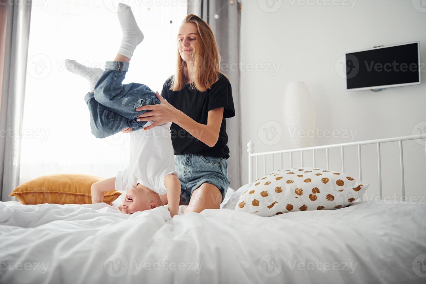 madre giocando e avere divertimento con sua figlio nel Camera da letto a giorno foto