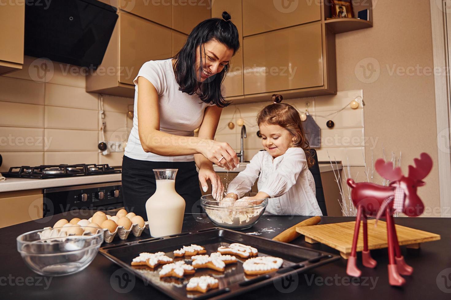 madre con sua poco figlia preparazione cibo su cucina e avere divertimento foto