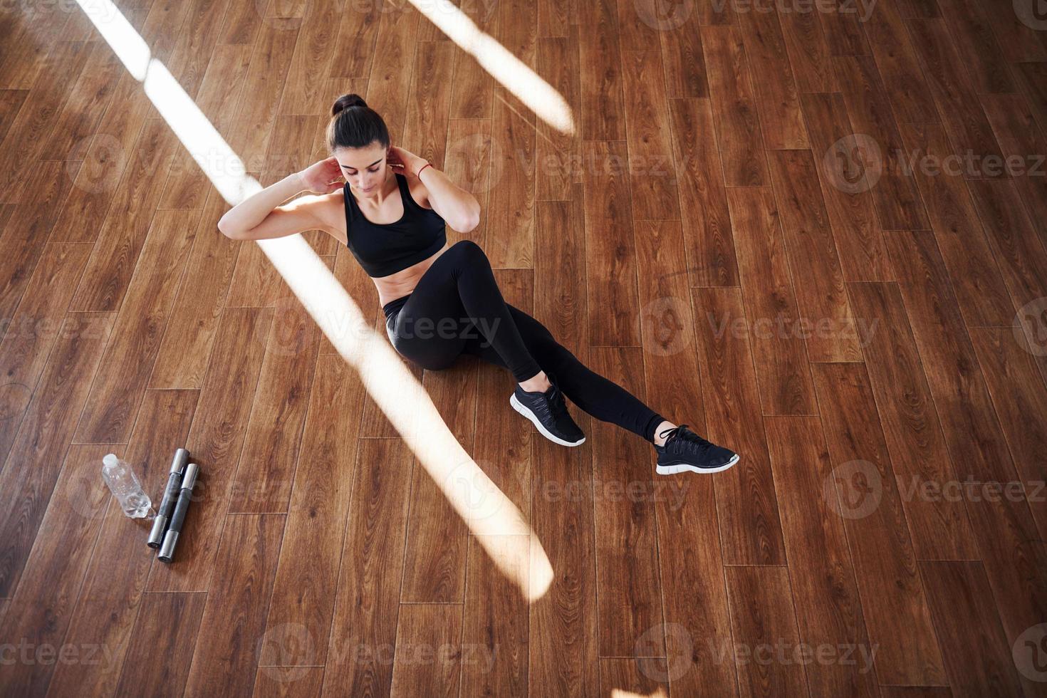 su il pavimento illuminato di leggero travi. giovane sportivo donna nel abbigliamento sportivo fare fitness nel il Palestra foto