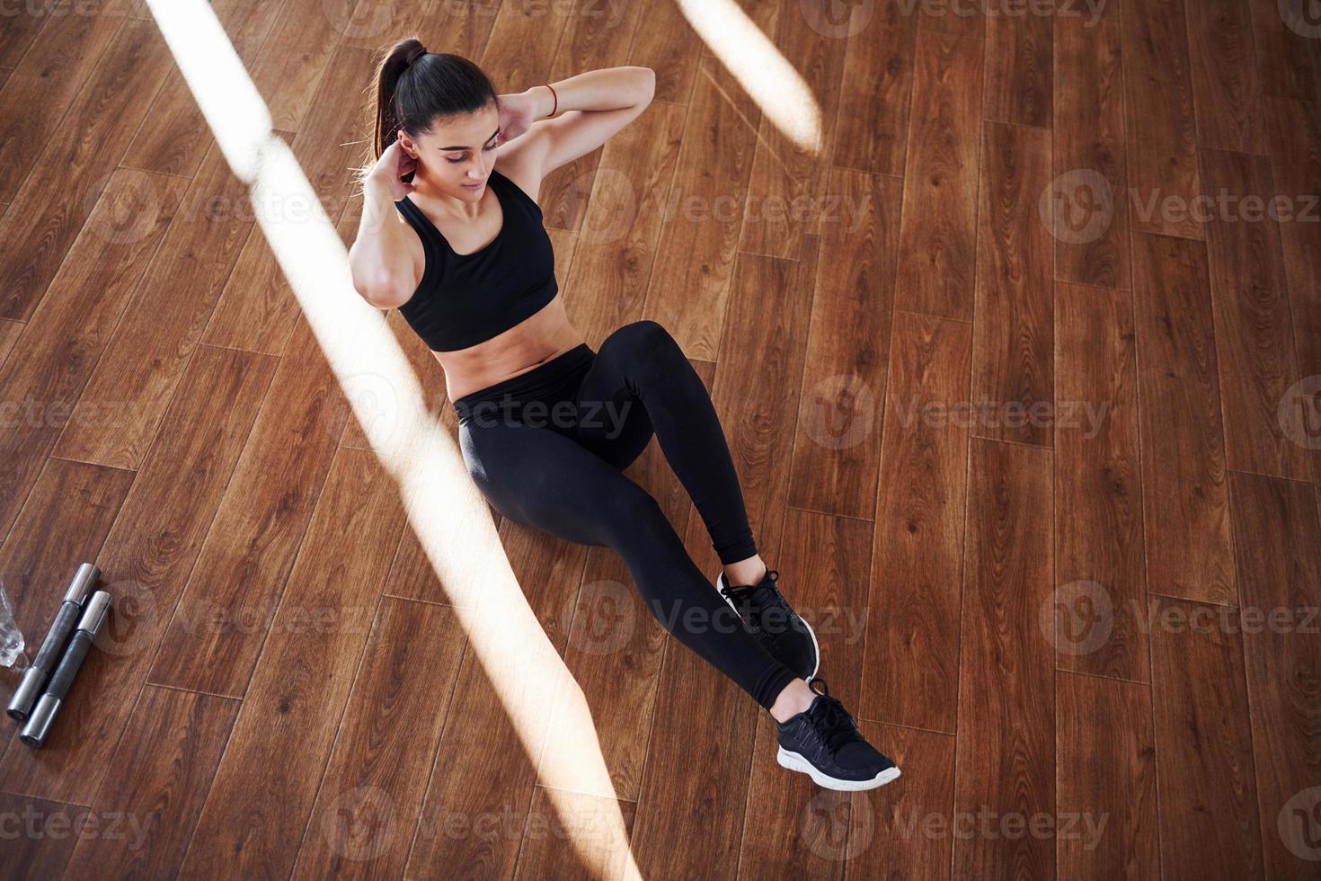 su il pavimento illuminato di leggero travi. giovane sportivo donna nel abbigliamento sportivo fare fitness nel il Palestra foto