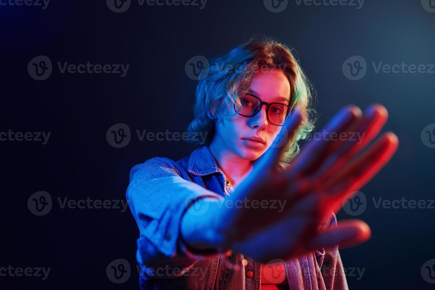 ritratto di giovane alternativa ragazza nel bicchieri con verde capelli nel rosso e blu neon leggero nel studio foto