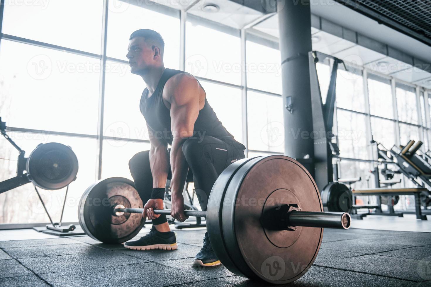 forte giovane uomo nel allegro Abiti fare esercizi con pesante pesi nel il Palestra foto