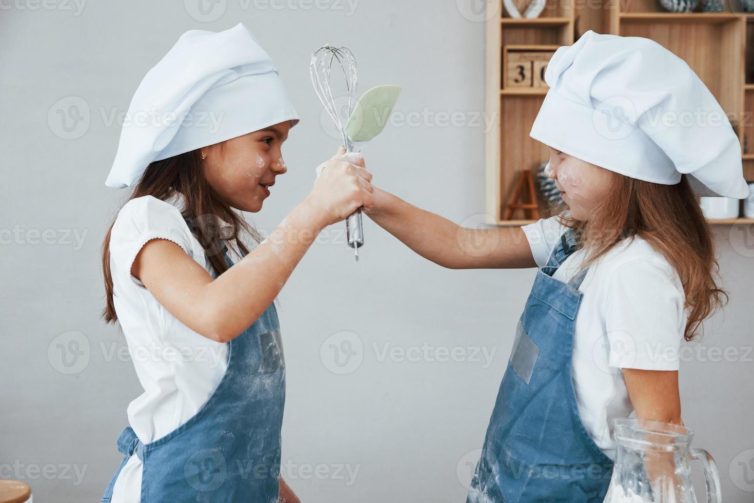 Due poco ragazze nel blu capocuoco uniforme preparazione cibo su il cucina foto