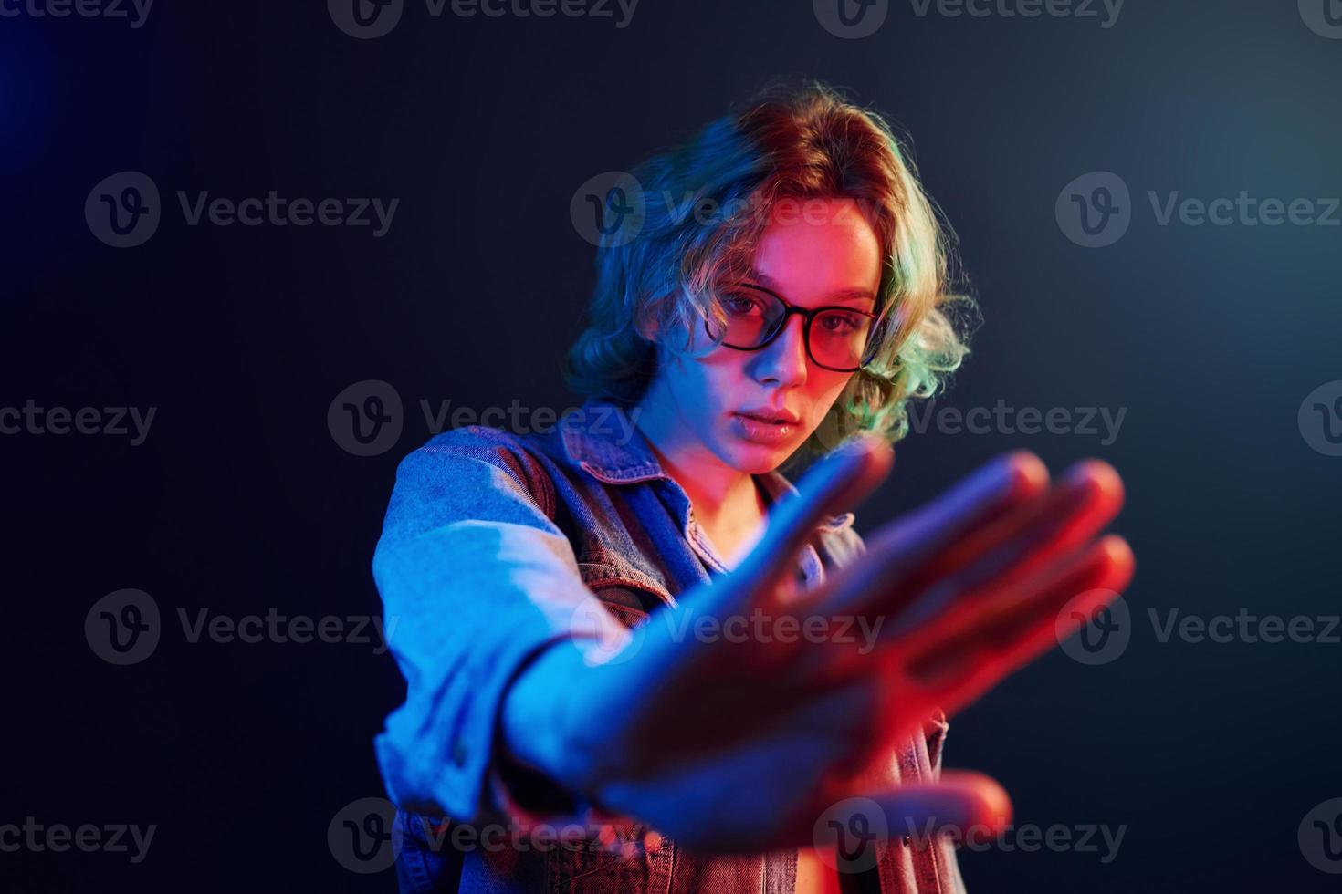 ritratto di giovane alternativa ragazza nel bicchieri con verde capelli nel rosso e blu neon leggero nel studio foto