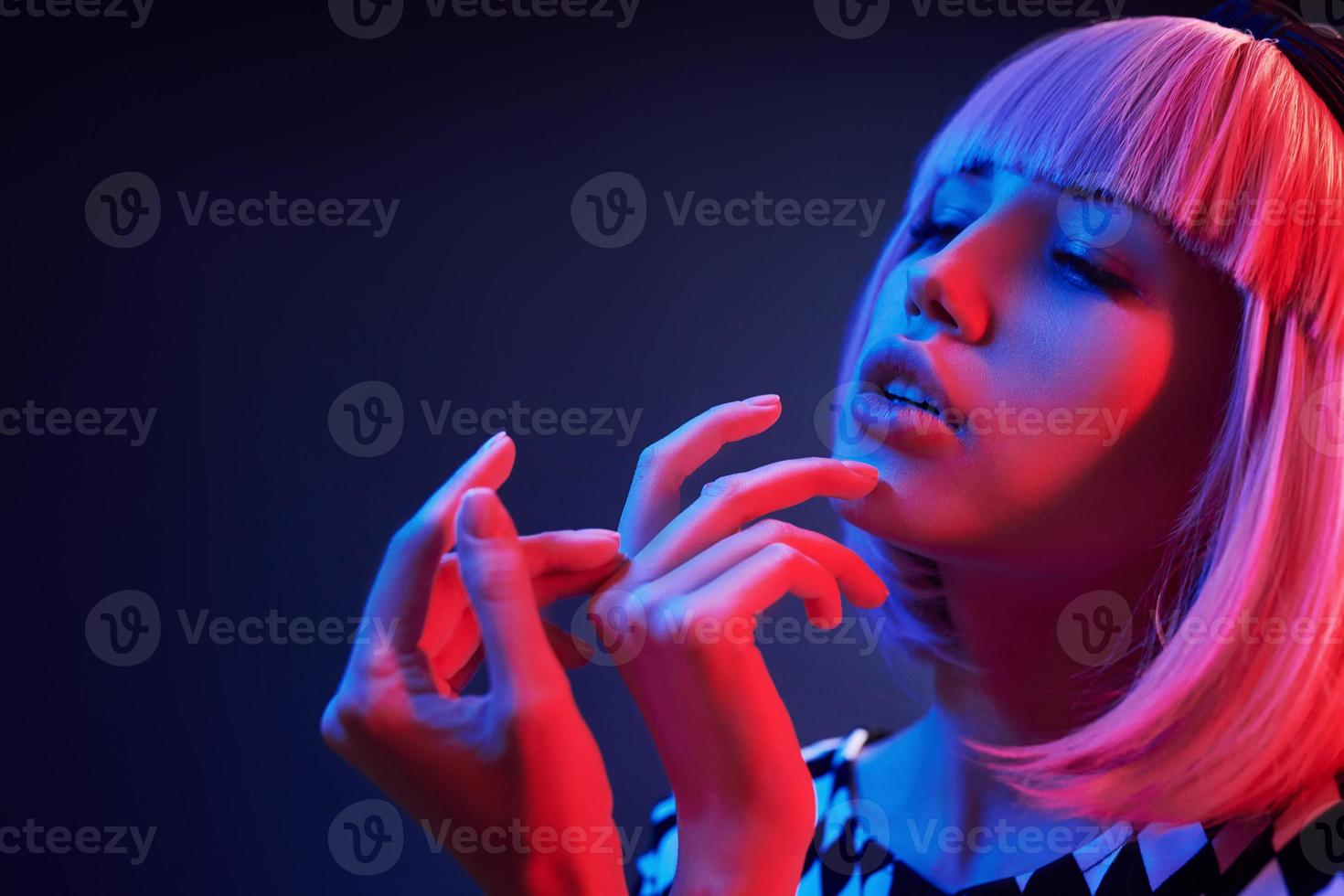 ritratto di giovane ragazza con biondo capelli nel rosso e blu neon nel studio foto