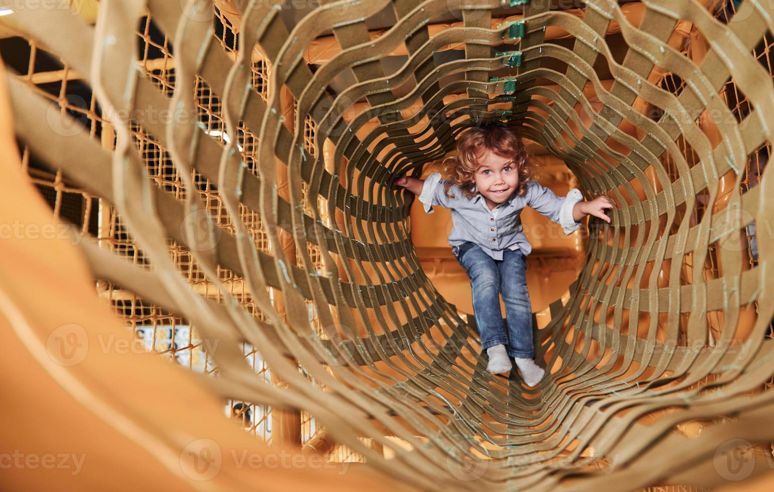 bambino avere divertimento nel stanza dei giochi di andando attraverso il di legno gabbia foto