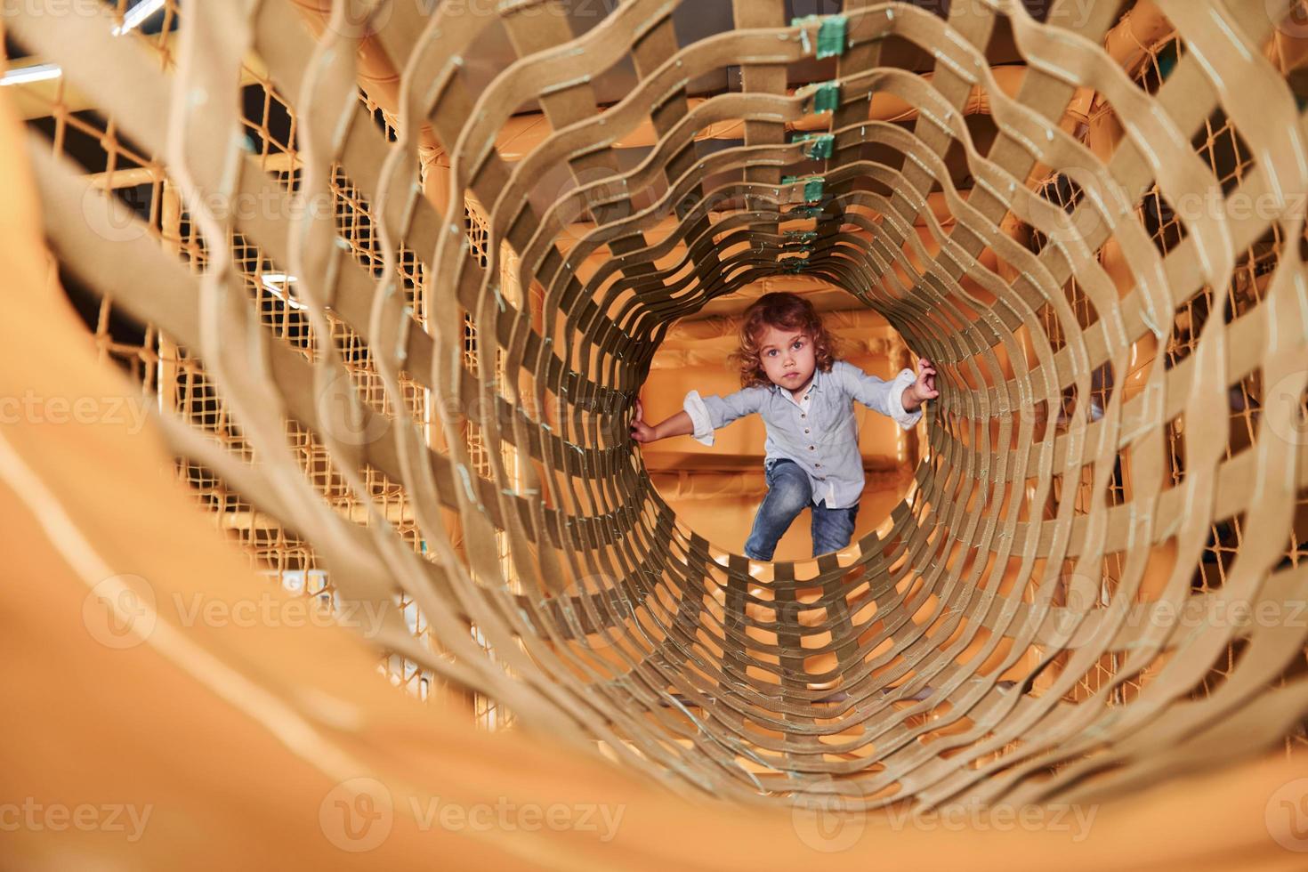 bambino avere divertimento nel stanza dei giochi di andando attraverso il di legno gabbia foto