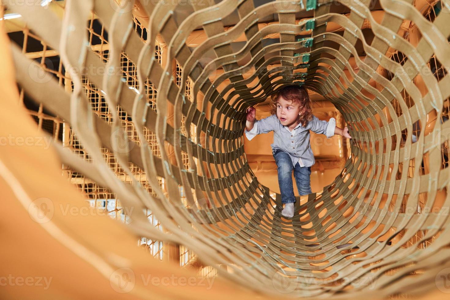 bambino avere divertimento nel stanza dei giochi di andando attraverso il di legno gabbia foto