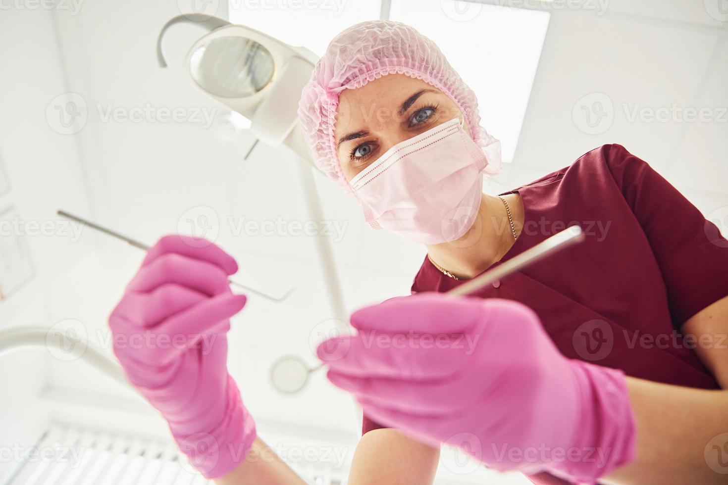 giovane femmina dentista nel protettivo maschera Lavorando nel stomatologia clinica. primo persona Visualizza foto