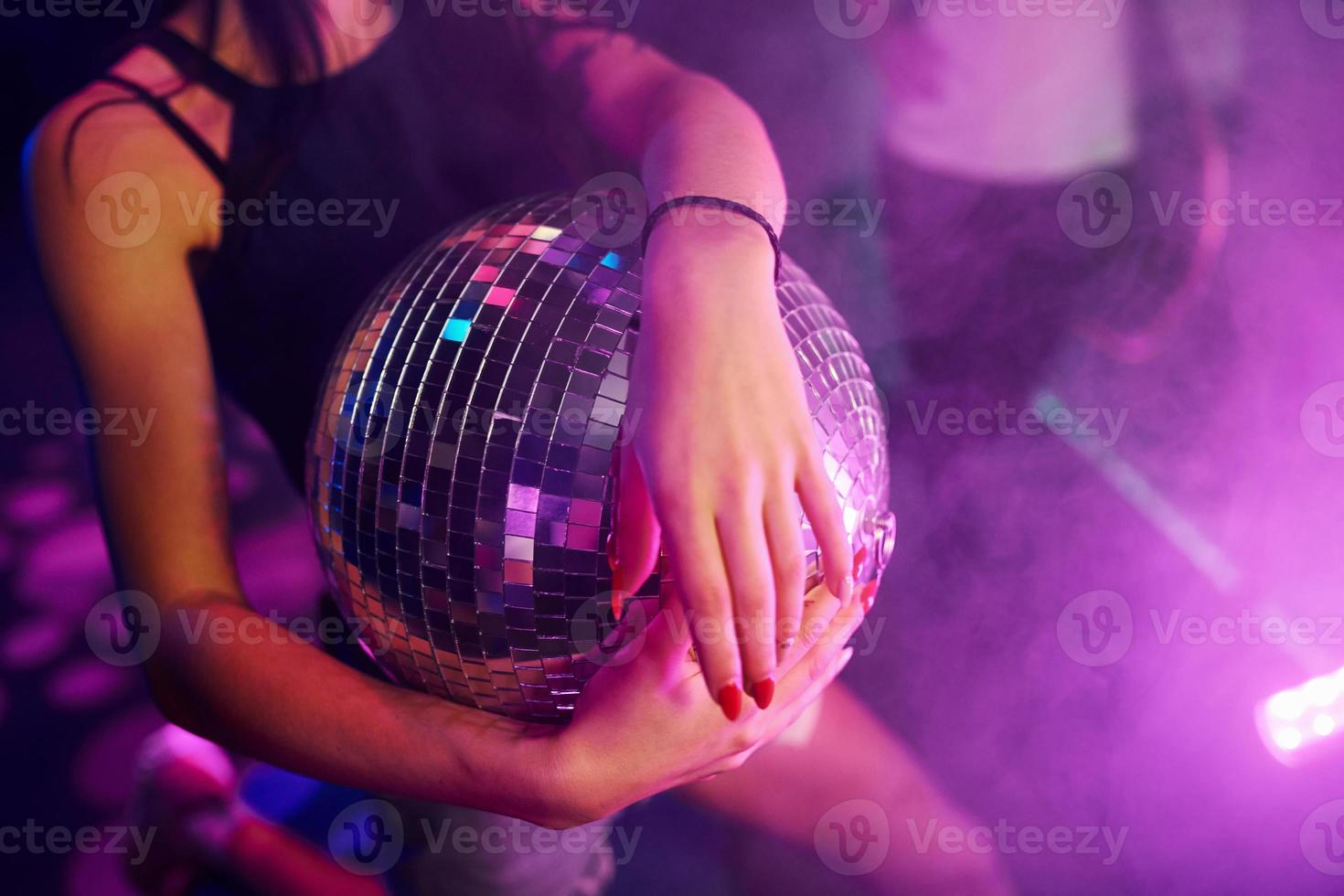 ragazza seduta dentro di notte club con festa palla nel mani foto