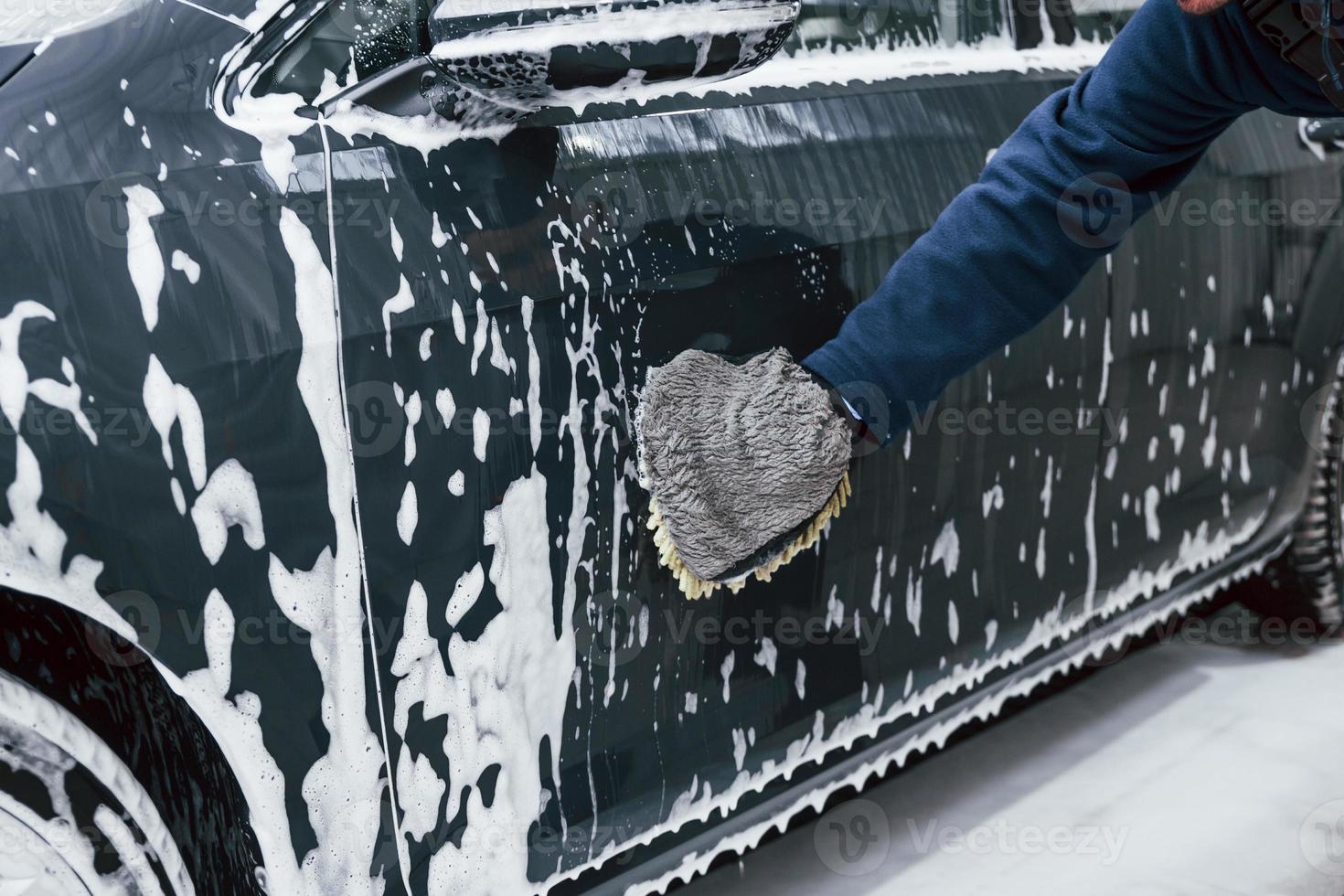 maschio lavoratore nel uniforme lavaggio nuovo moderno auto quello è pieno di sapone. concezione di servizio foto