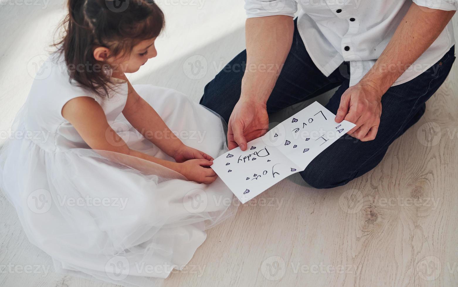 contento Il padre di giorno. figlia fa sorpresa per papà di dando cartolina con cuore foto