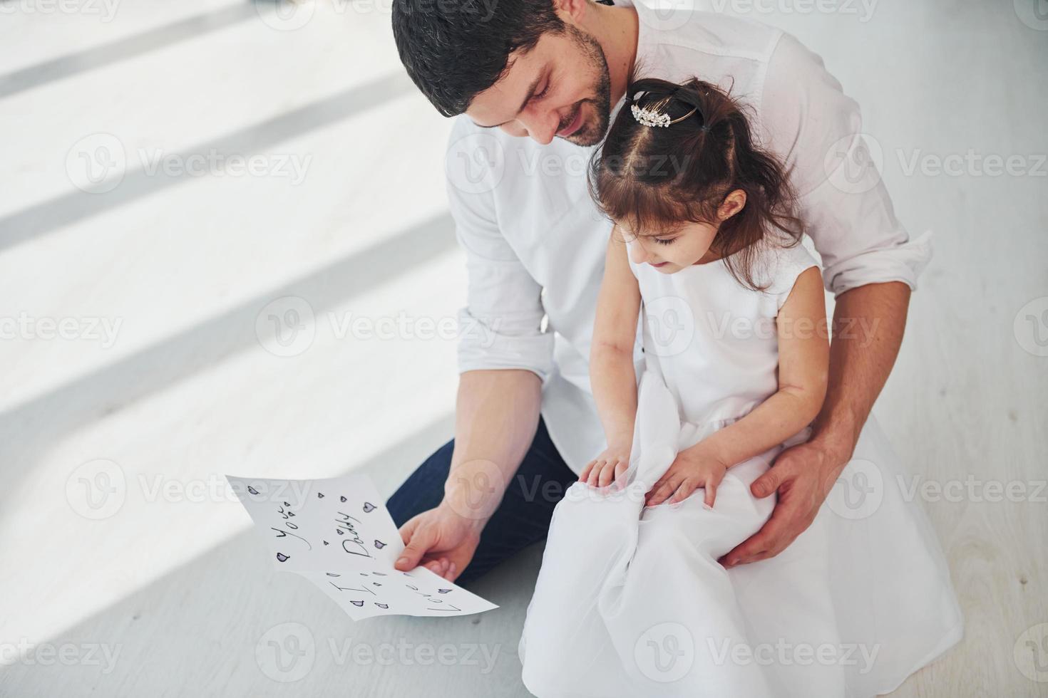 contento Il padre di giorno. figlia fa sorpresa per papà di dando cartolina con cuore foto