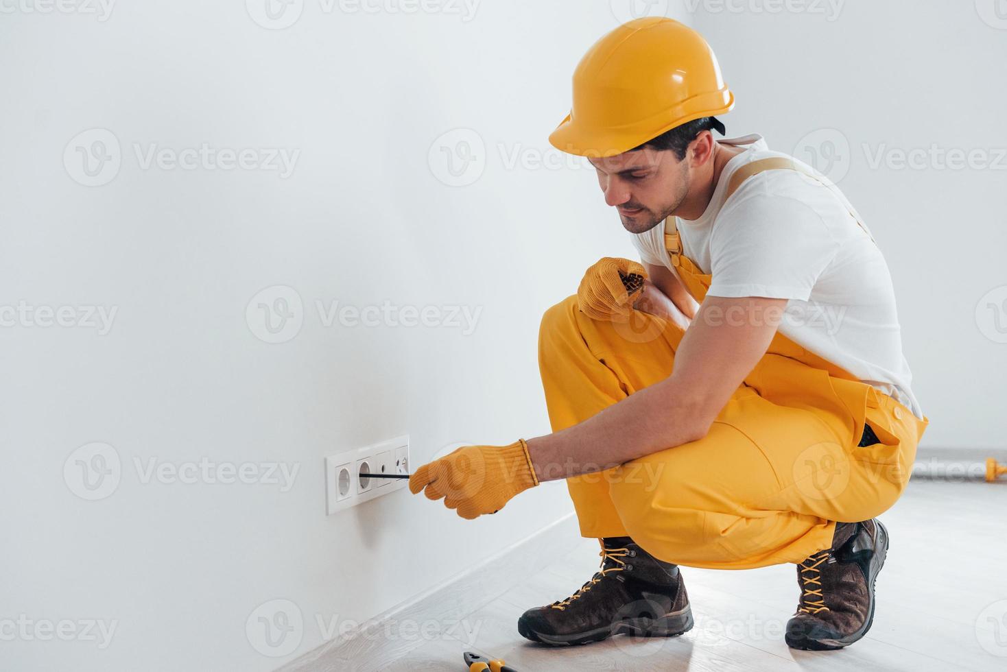 tuttofare nel giallo uniforme lavori con elettricità e installazione nuovo PRESA. Casa rinnovamento concezione foto