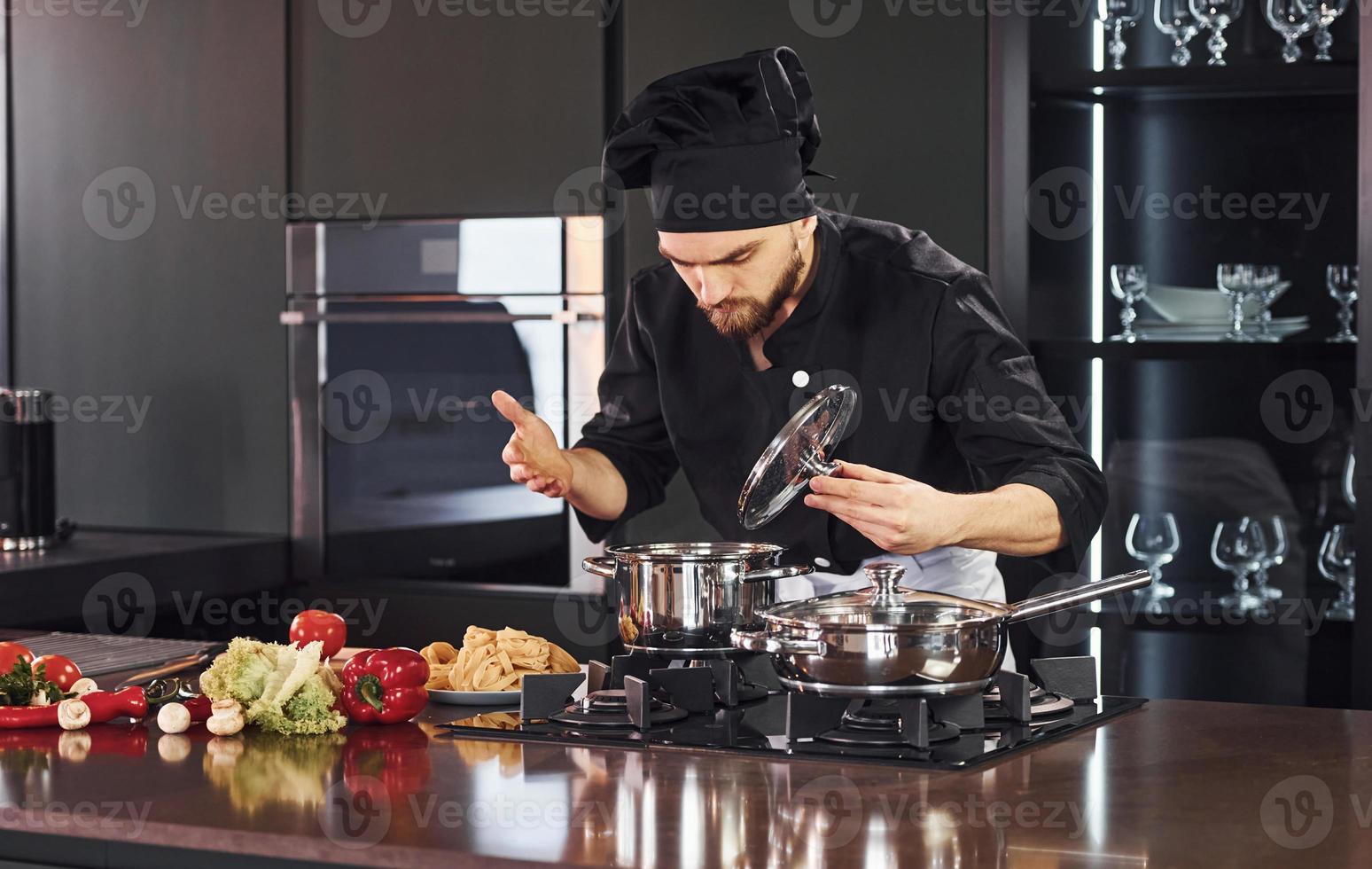 utilizzando attrezzatura. professionale giovane capocuoco cucinare nel uniforme Lavorando su il cucina con verdure foto