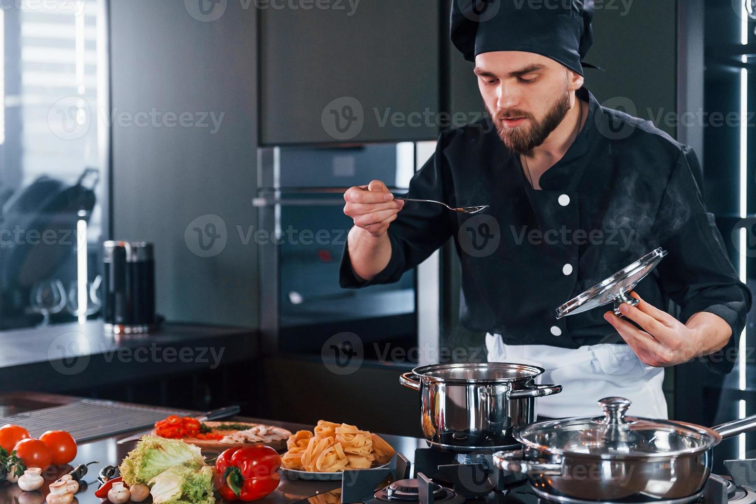 professionale giovane capocuoco cucinare nel uniforme Lavorando su il cucina foto