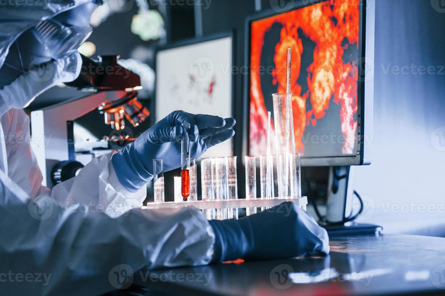 scienziato nel bianca protettivo uniforme lavori con coronavirus e sangue tubi nel laboratorio foto