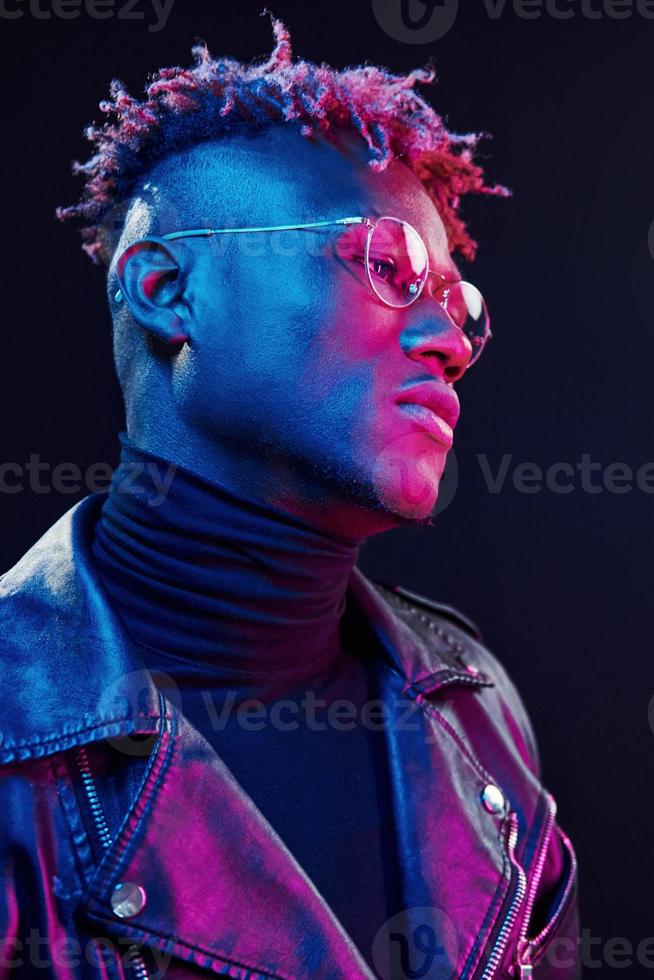 nel occhiali. futuristico neon illuminazione. giovane africano americano uomo nel il studio foto