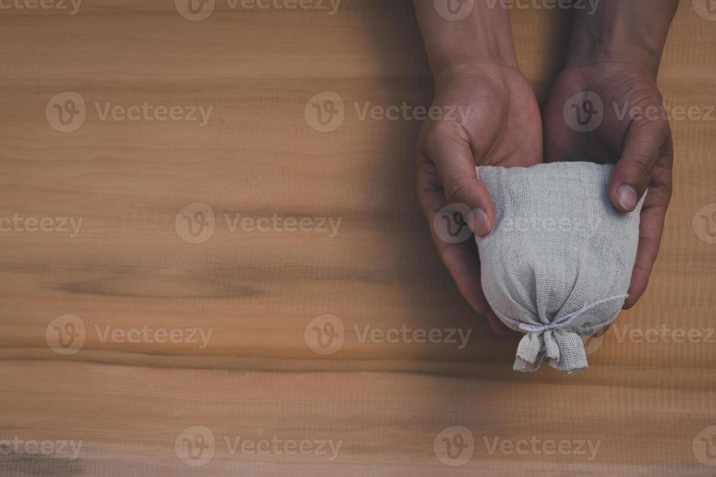 superiore Visualizza di mani Tenere i soldi Borsa su il di legno tavolo sfondo foto