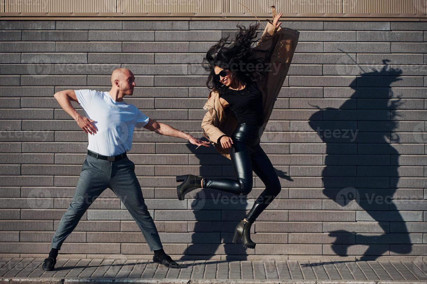 bellissimo coppia nel nero Abiti danza insieme contro parete all'aperto foto