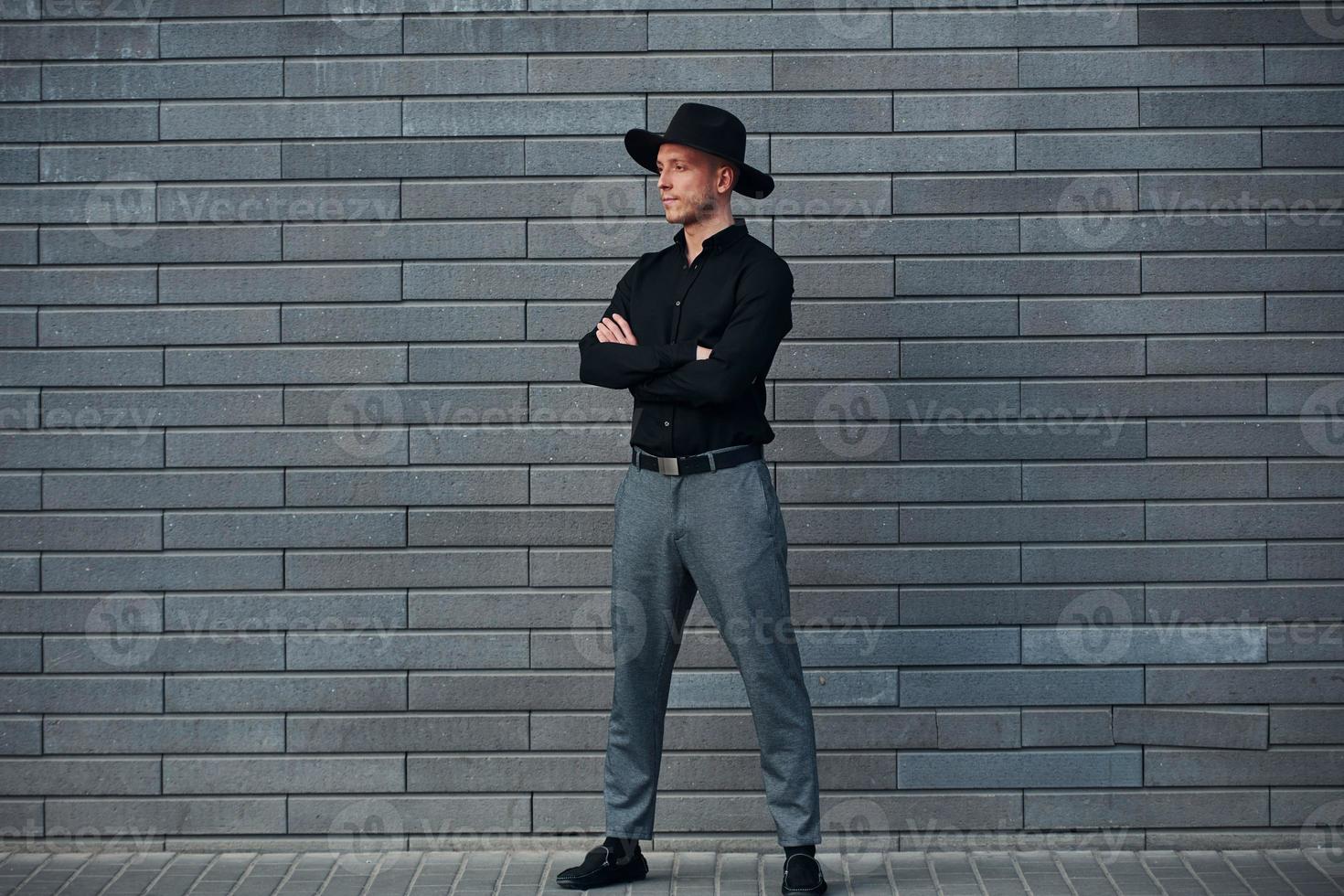 alla moda elegante uomo in piedi all'aperto contro grigio parete foto