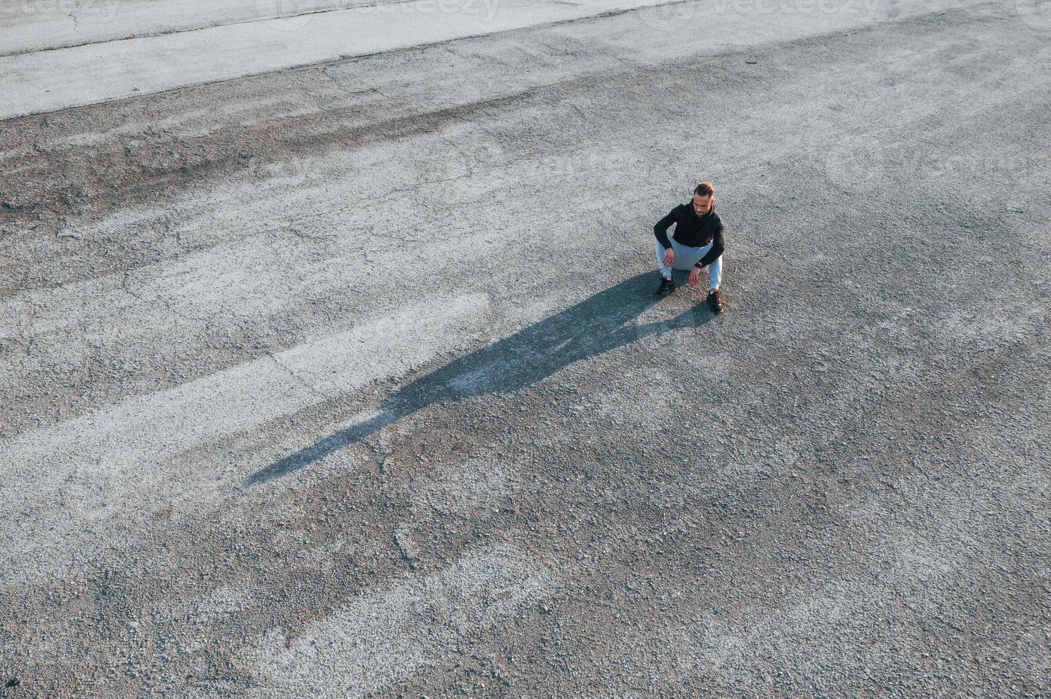 superiore Visualizza di uomo quello seduta su il strada a sera solo foto