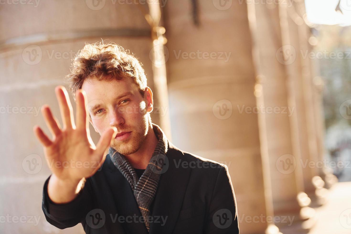 Spettacoli fermare gesto di il mano. elegante giovane uomo nel formale di classe Abiti all'aperto nel il città foto