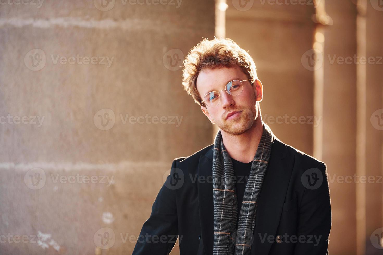 ritratto di elegante giovane uomo nel bicchieri e formale di classe Abiti all'aperto nel il città foto