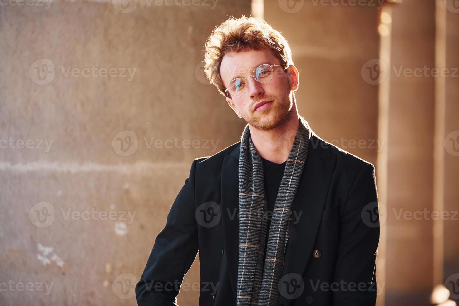 ritratto di elegante giovane uomo nel bicchieri e formale di classe Abiti all'aperto nel il città foto