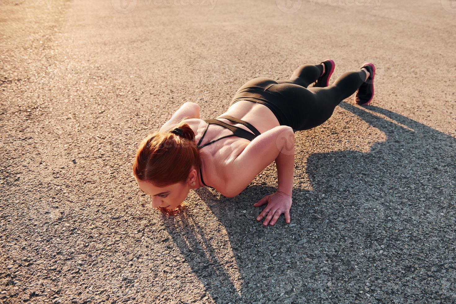 donna nel abbigliamento sportivo fare sollevamento su il strada a sera tempo foto