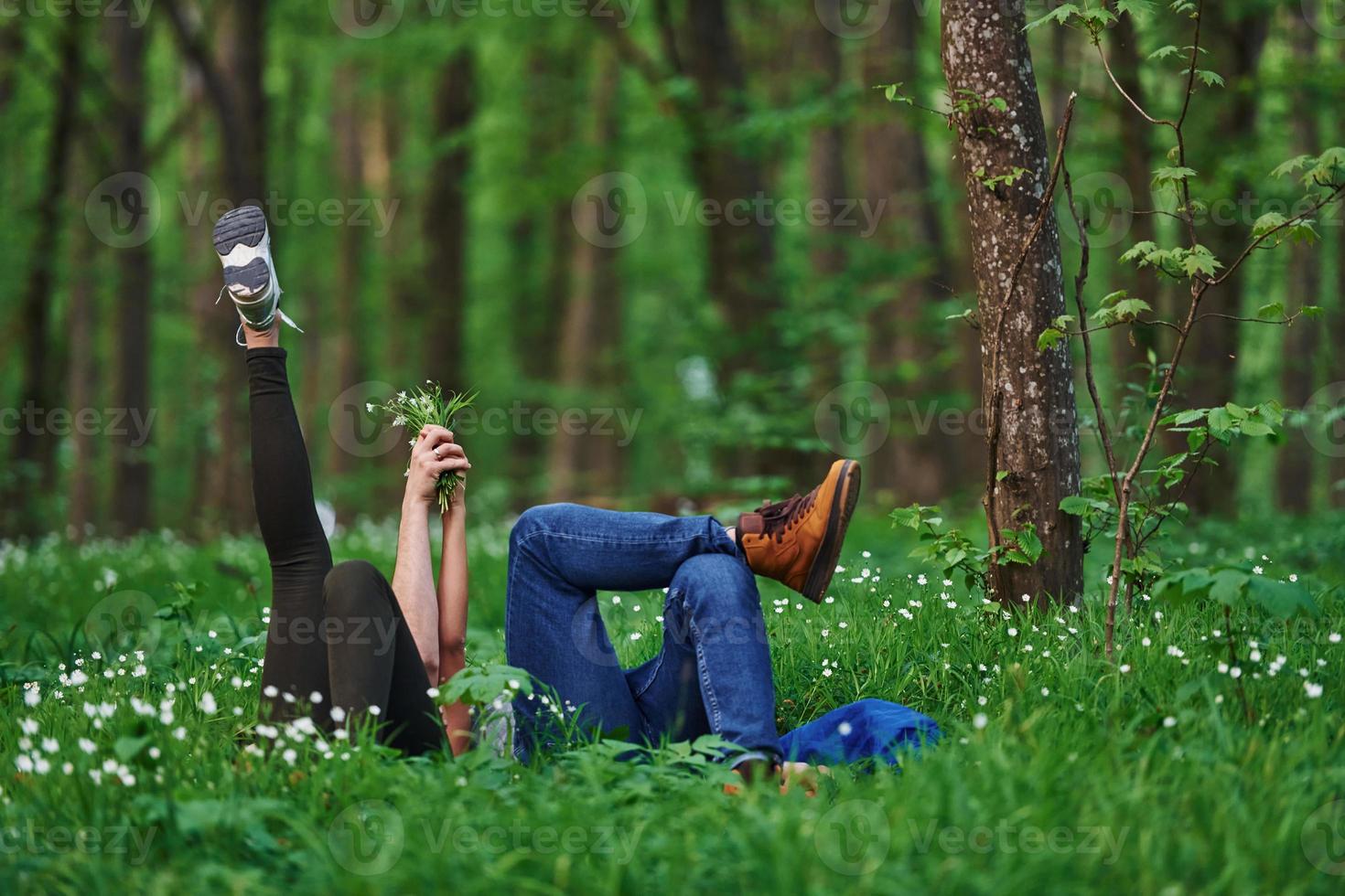 coppia dire bugie giù su il erba nel foresta insieme a giorno foto