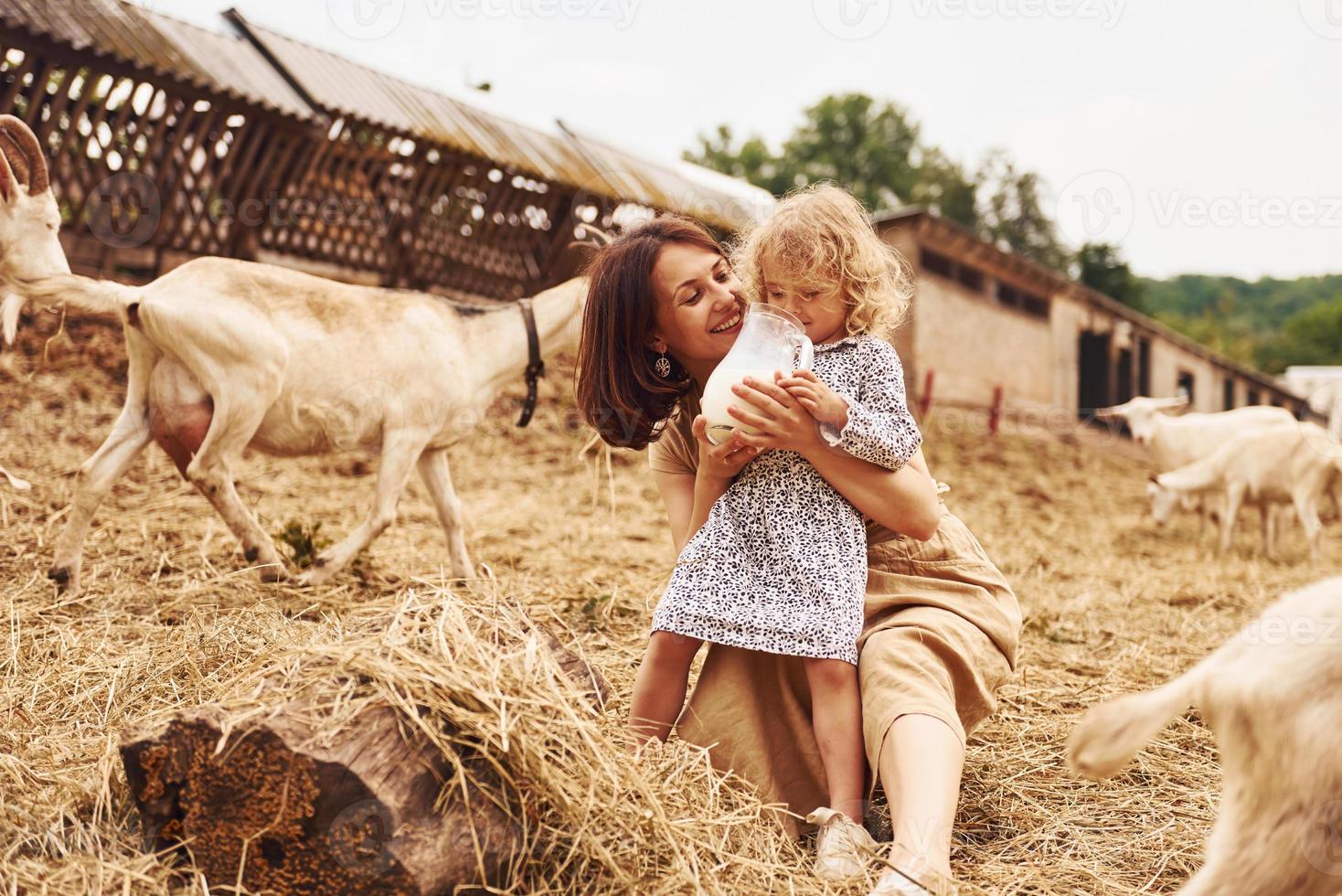 giovane madre con sua figlia è su il azienda agricola a estate con capre foto