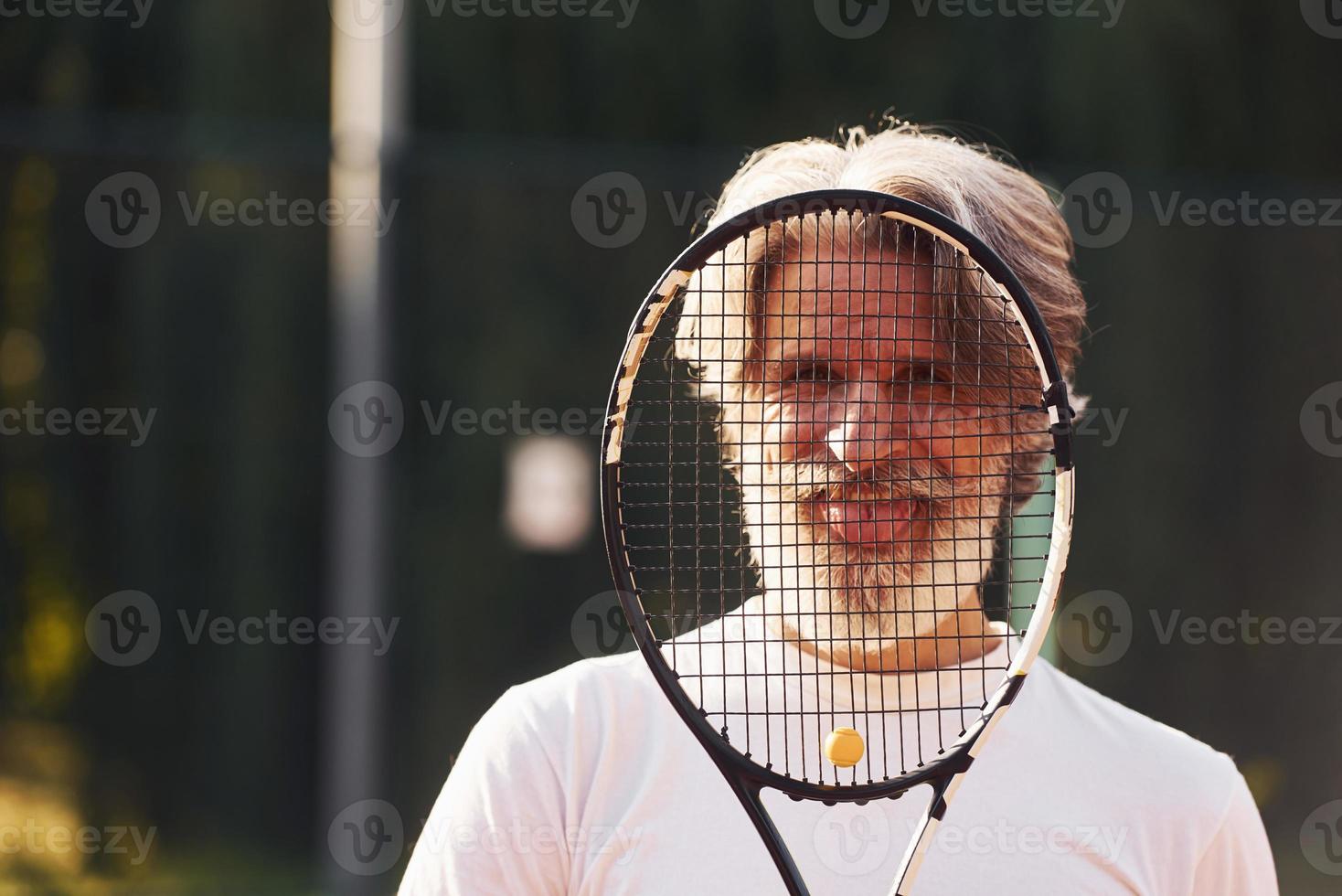 anziano elegante uomo nel bianca camicia e nero allegro pantaloncini su tennis Tribunale foto