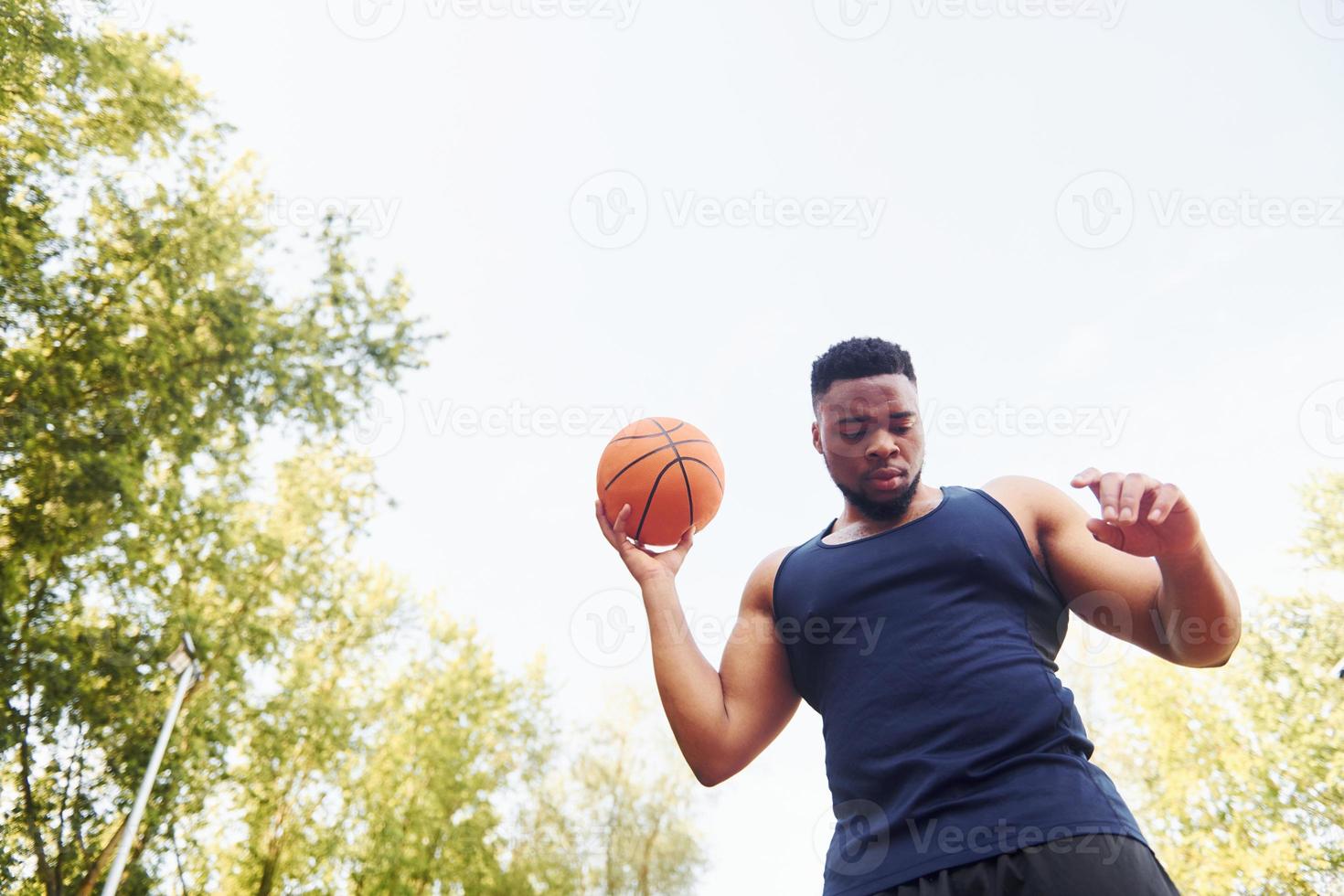 nuvoloso tempo atmosferico. africano americano uomo giochi pallacanestro su il Tribunale all'aperto foto