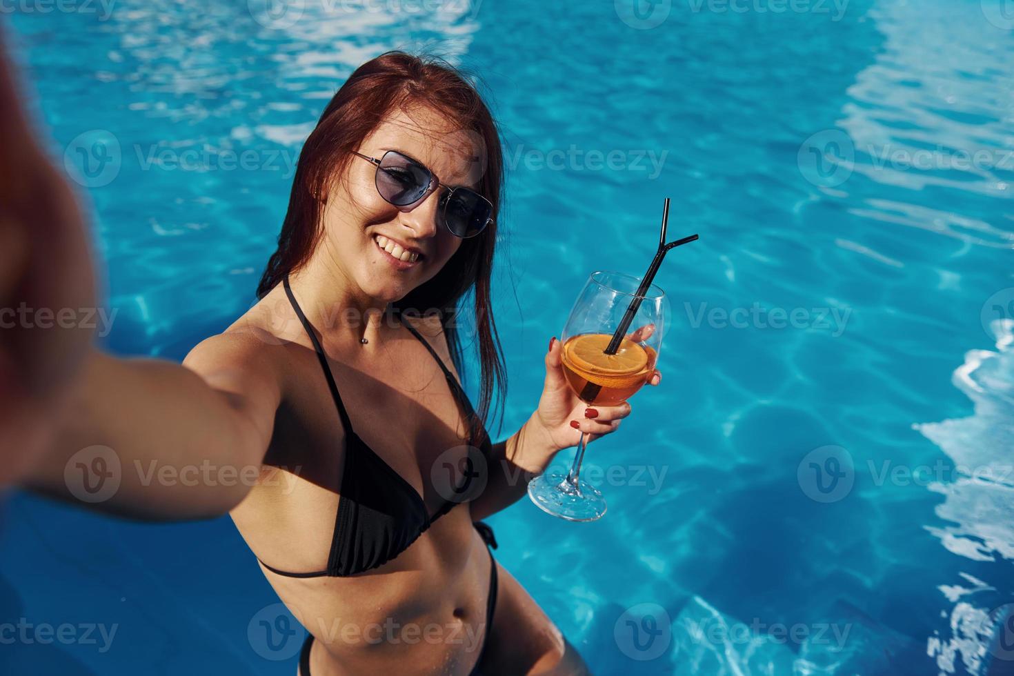 ragazza nel occhiali da sole avere divertimento e riposo nel nuoto piscina a giorno foto