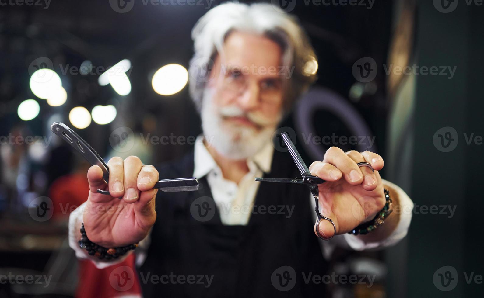 nel barbiere. elegante moderno anziano uomo con grigio capelli e barba è in casa foto