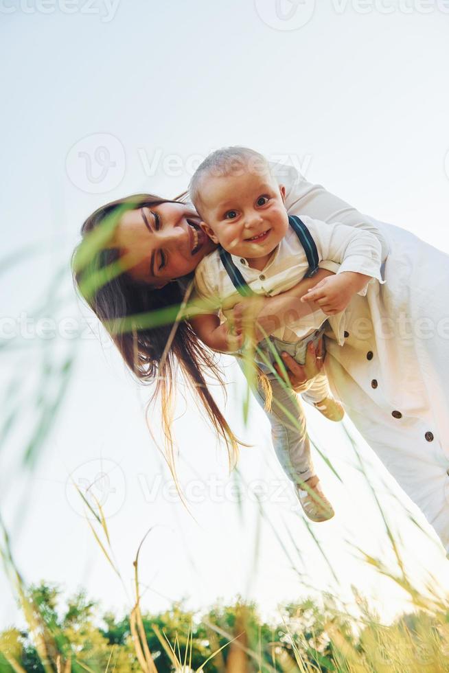 contento famiglia sorridente e avendo divertimento. giovane madre con sua poco figlio è all'aperto nel il agricolo campo. bellissimo luce del sole foto