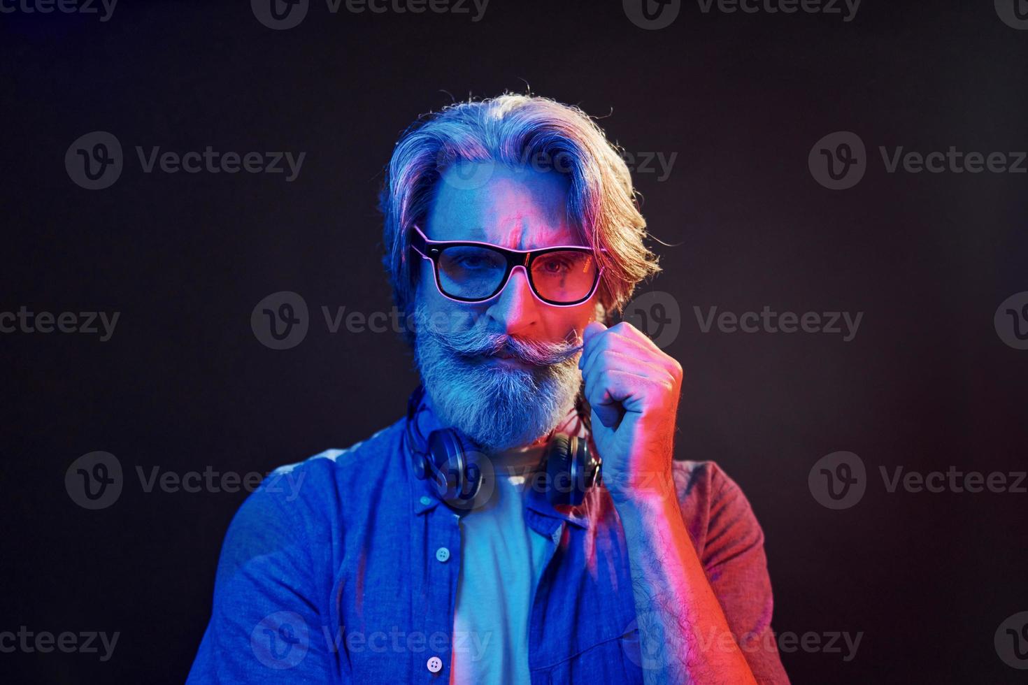 neon illuminazione, concezione di festa. elegante moderno anziano uomo con grigio capelli e barba è in casa foto