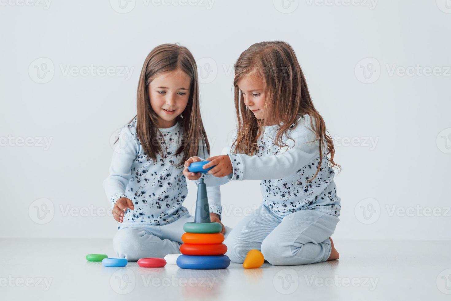 giocando con giocattolo. Due carino poco ragazze in casa a casa insieme. bambini avendo divertimento foto