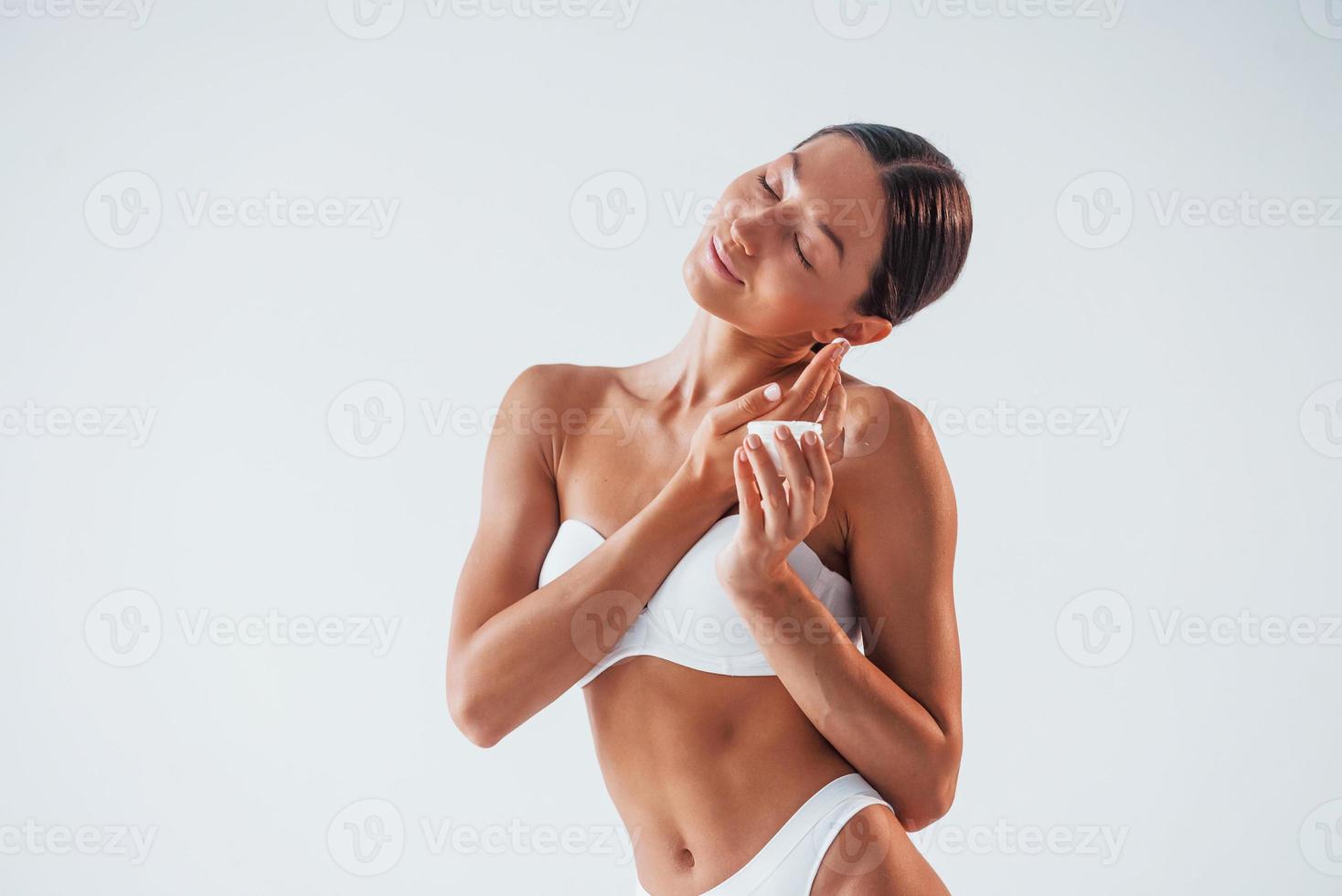 concezione di bellezza. utilizzando crema. donna con sottile corpo nel biancheria intima è nel il studio foto