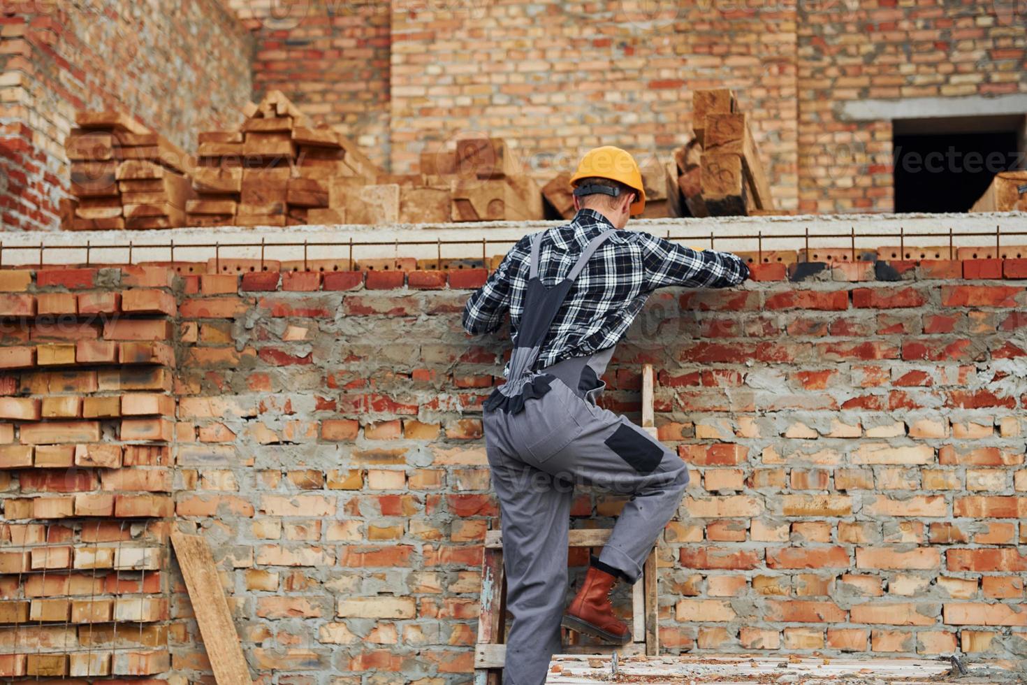 si arrampica su. costruzione lavoratore nel uniforme e sicurezza attrezzatura avere lavoro su edificio foto