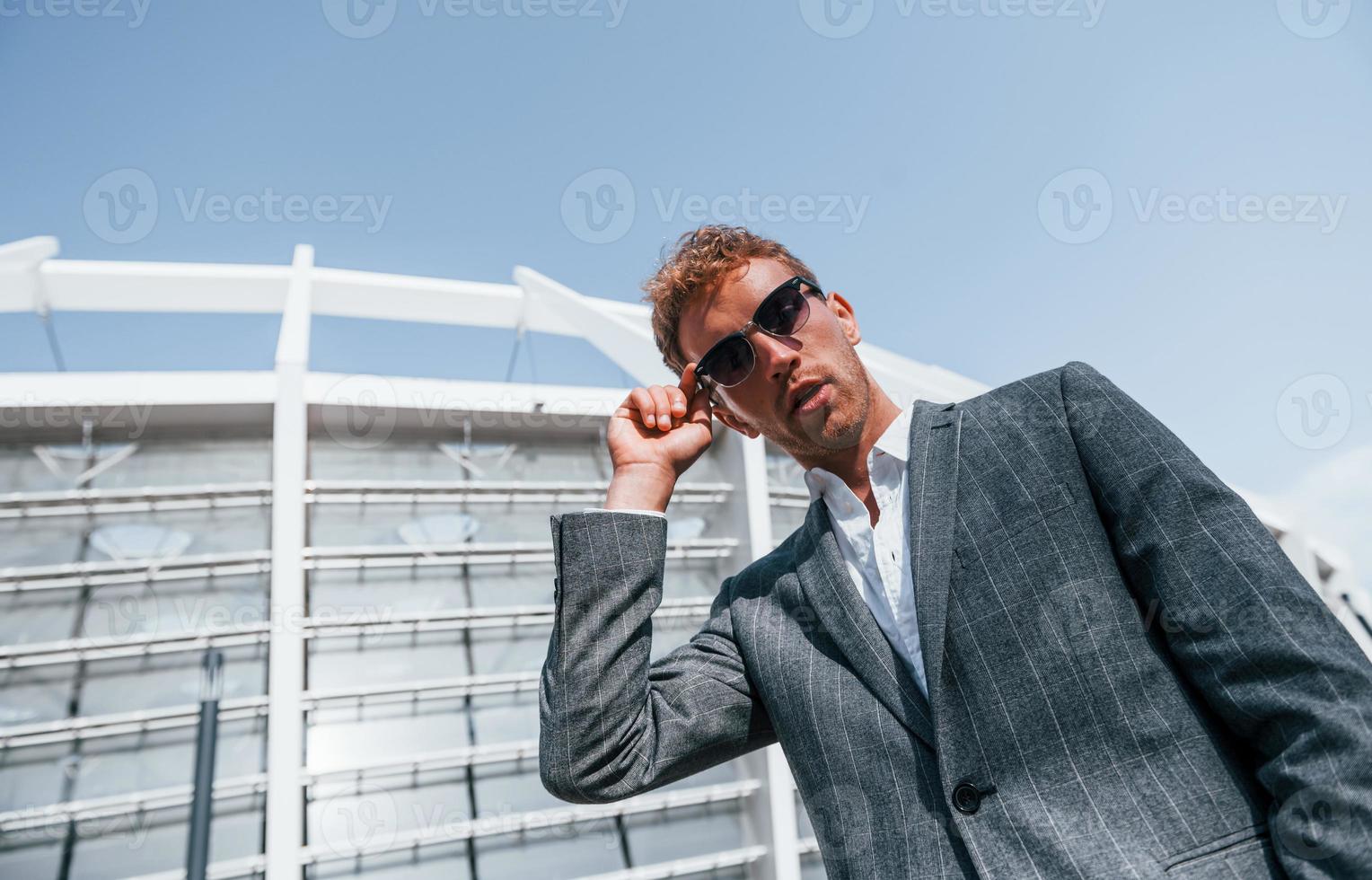 grande stadio dietro. giovane uomo d'affari nel grigio formale indossare è all'aperto nel il città foto