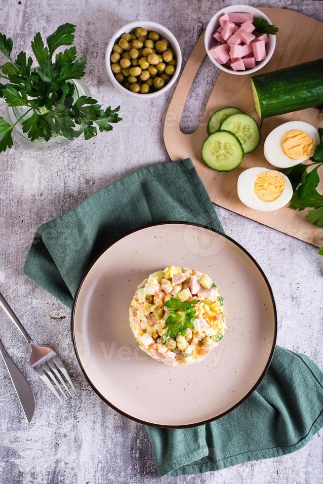 tradizionale russo olivier insalata di bollito verdure e salsicce su un' piatto. superiore e verticale foto