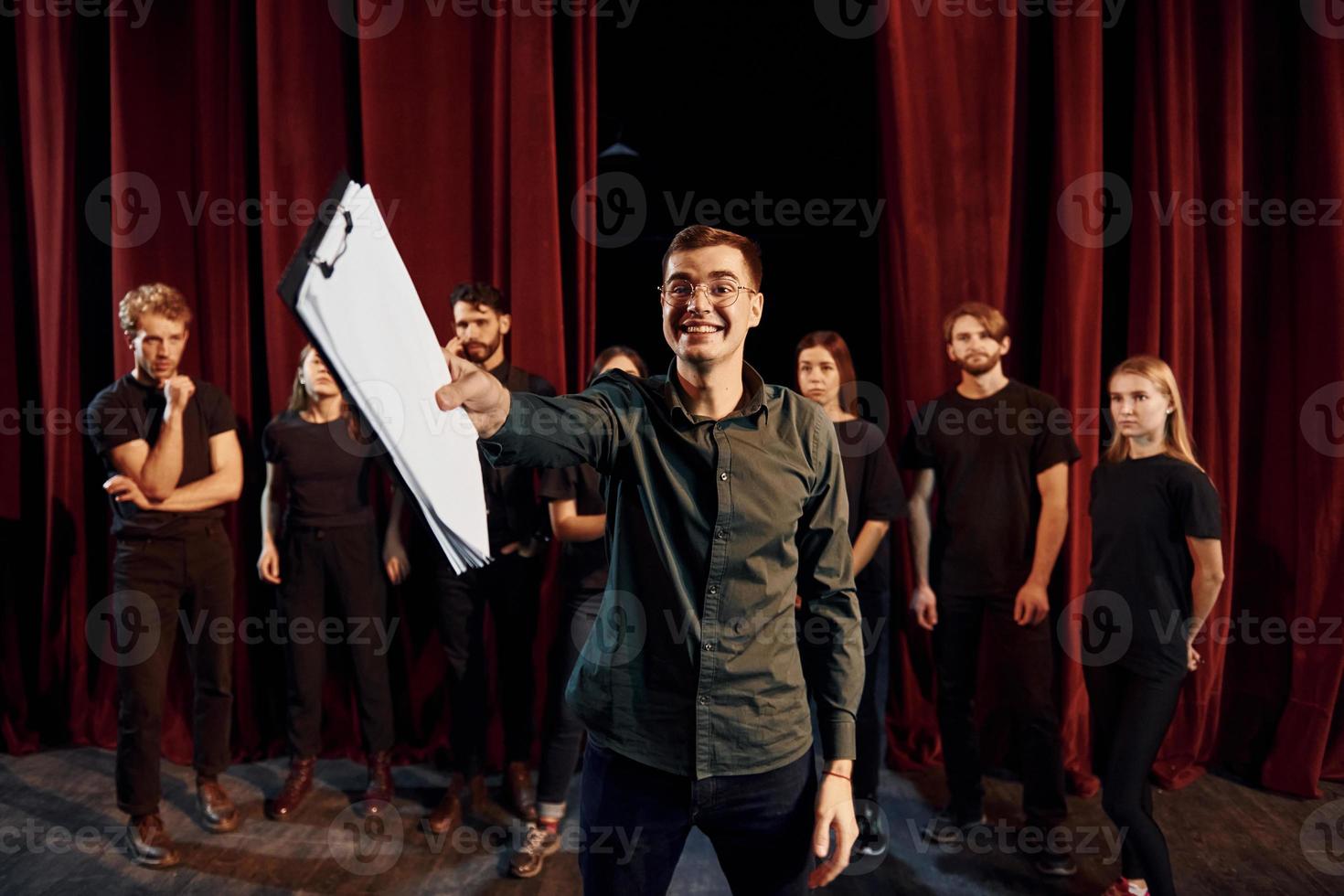 uomo è praticante il suo ruolo. gruppo di attori nel buio colorato Abiti su prova nel il Teatro foto