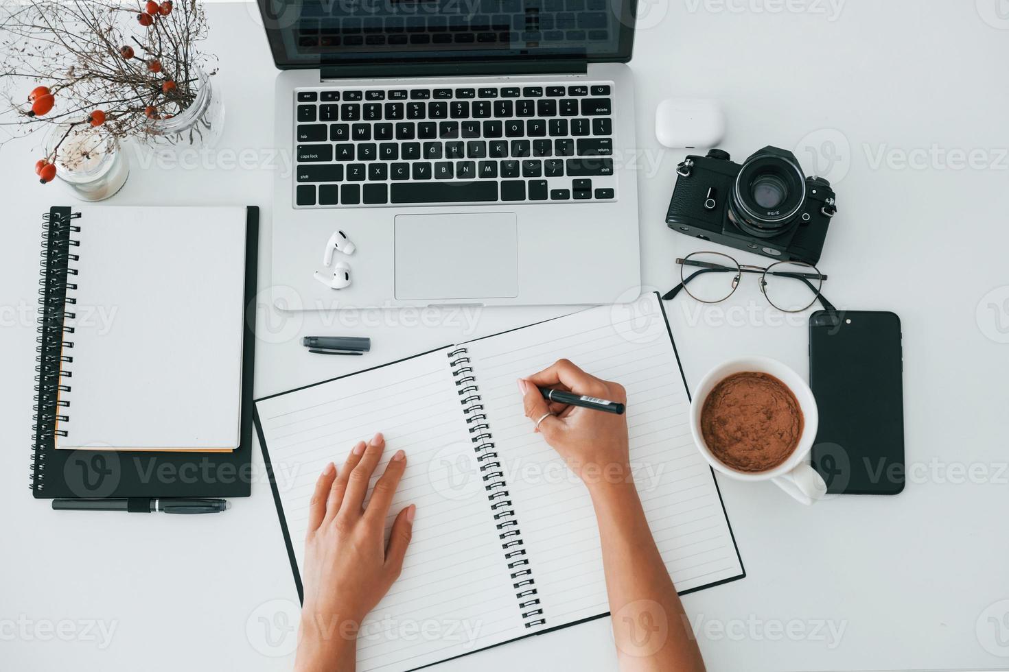 superiore Visualizza. giovane femmina libero professionista Lavorando in casa nel il ufficio a giorno. il computer portatile e bloc notes foto