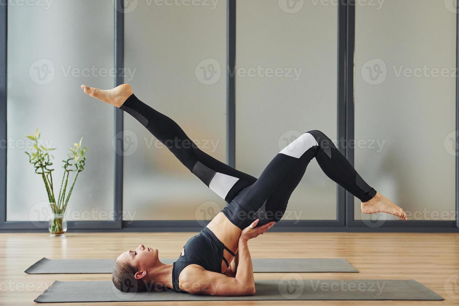 su il stuoia. giovane donna nel allegro indossare e con sottile corpo avere fitness yoga giorno in casa foto